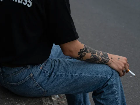 Casual Man Sitting with Tattooed Arm and Cigarette