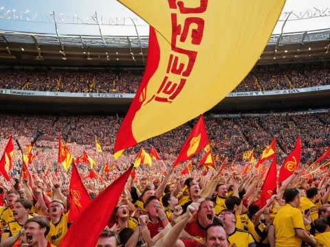 Energetic Crowd Cheering with Red and Yellow Flags at Stadium