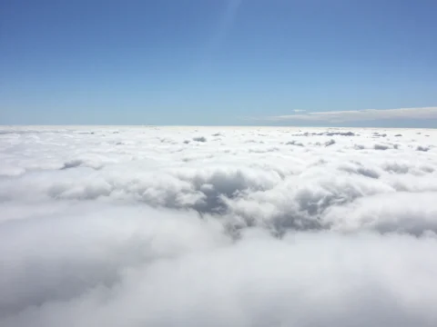 Expansive View Above the Clouds Under Clear Blue Sky