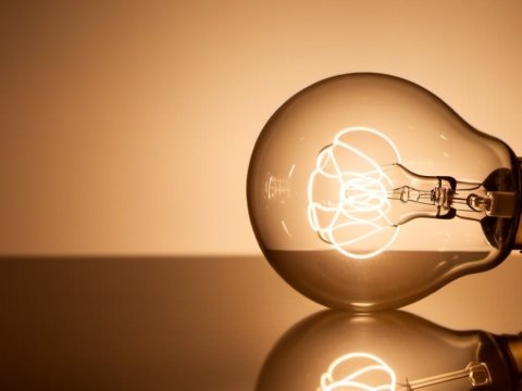 Glowing Light Bulb with Reflection on Surface