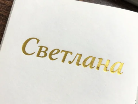 Golden Embossed Cyrillic Text on White Paper
