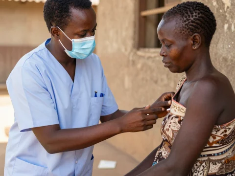 Health Worker Explains Vaccination to Woman in Outdoor Setting