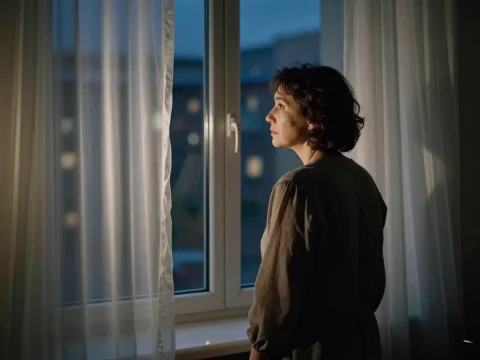 Lonely Woman Gazing Through Window at Dusk