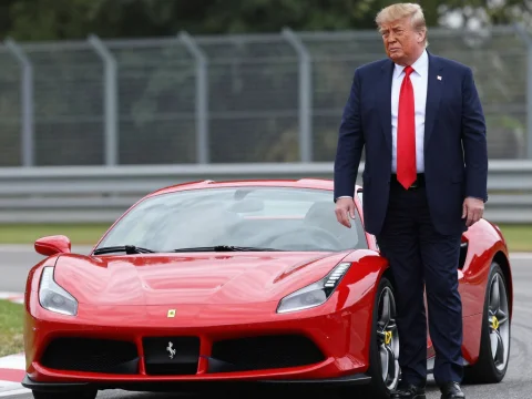 Man in Suit Standing Next to Red Ferrari on Race Track