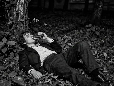 Man Reclining in Forest Drinking from Glass at Night