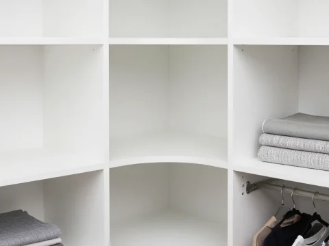 Minimalist White Corner Closet with Folded Clothes and Hanging Shirts