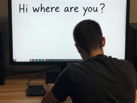 Person Facing Computer Screen with Message 'Hi where are you?'