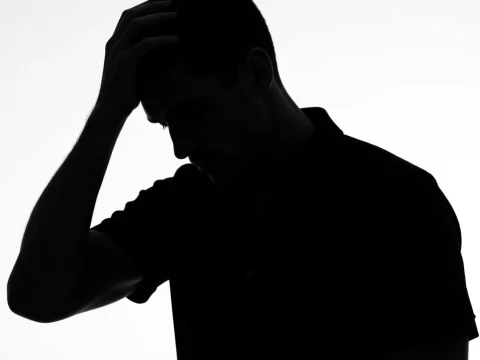 Silhouette of Man Holding Head in Thought