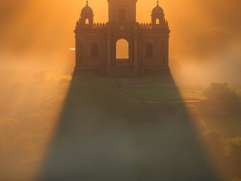 Silhouetted Guardian Approaching a Majestic Sunlit Castle