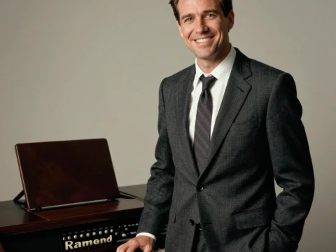 Smiling Man in Suit Standing by Vintage Keyboard