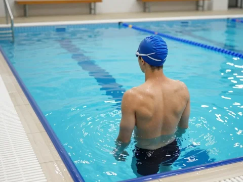 Swimmer Standing in Indoor Lap Pool Corner