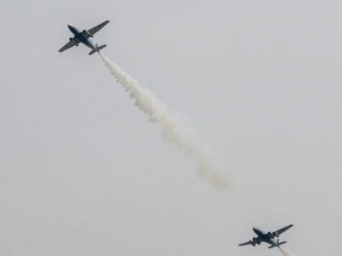 Two Airplanes Emitting Smoke Trails in Overcast Sky