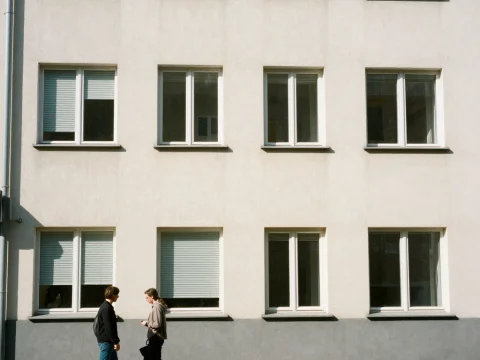 Two People Walking Past a Modern Apartment Building