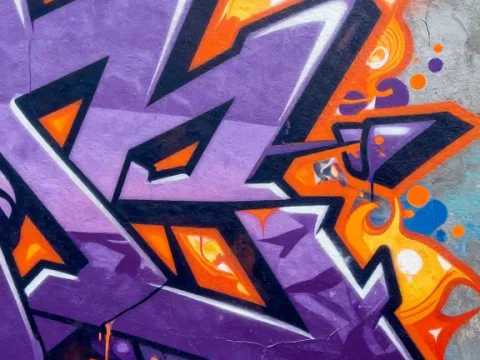 Vibrant Purple and Orange Graffiti Mural on Concrete Wall