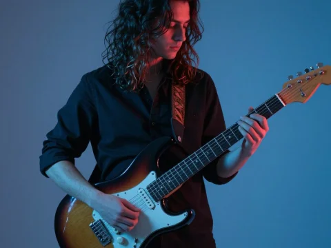 Young Man Playing Electric Guitar in Blue Lighting