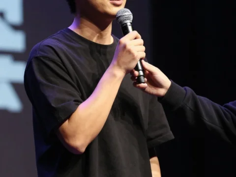 Young Man Speaking on Stage with Microphone