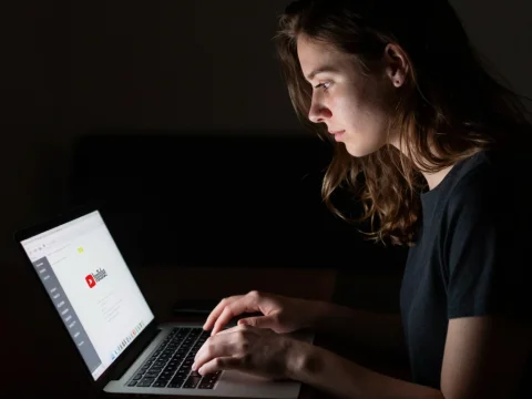 Young Woman Using Laptop in Dimly Lit Room